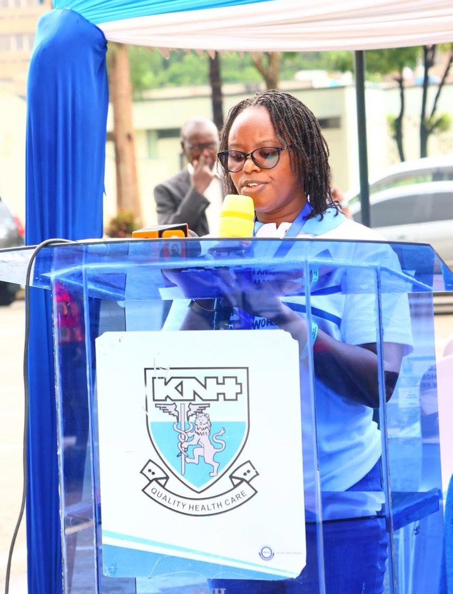 Dr. Janet Mwau speaking into a microphone at a lectern bearing the Kenyatta National Hospital crest, during the World Lymphoedema Day commemoration.